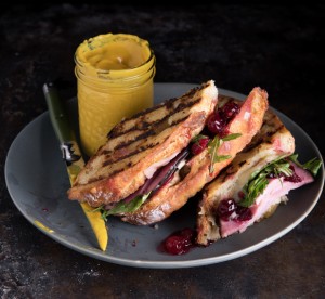 Grilled ham and cheese sandwich on plate with knife and mustard