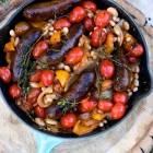 sausage and beans in cast iron pan on a tree stump