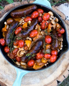 sausage and beans in cast iron pan on a tree stump