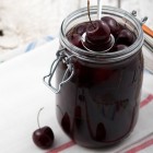 jar of pickles cherries, with cherries loosely layout outside of the jar