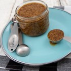 jar of bourbon and brown sugar mustard, with spoon, on a blue plate