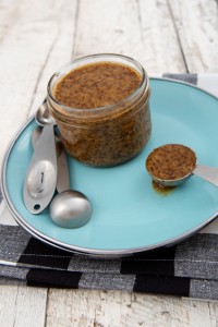 jar of bourbon and brown sugar mustard, with spoon, on a blue plate