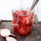 jar of pickled radishes, with spoon in jar and on a serving platter
