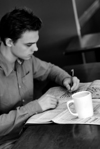 man at table writing, with coffee cup next to him
